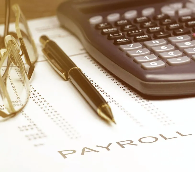 Payroll documents and a pen on a desk