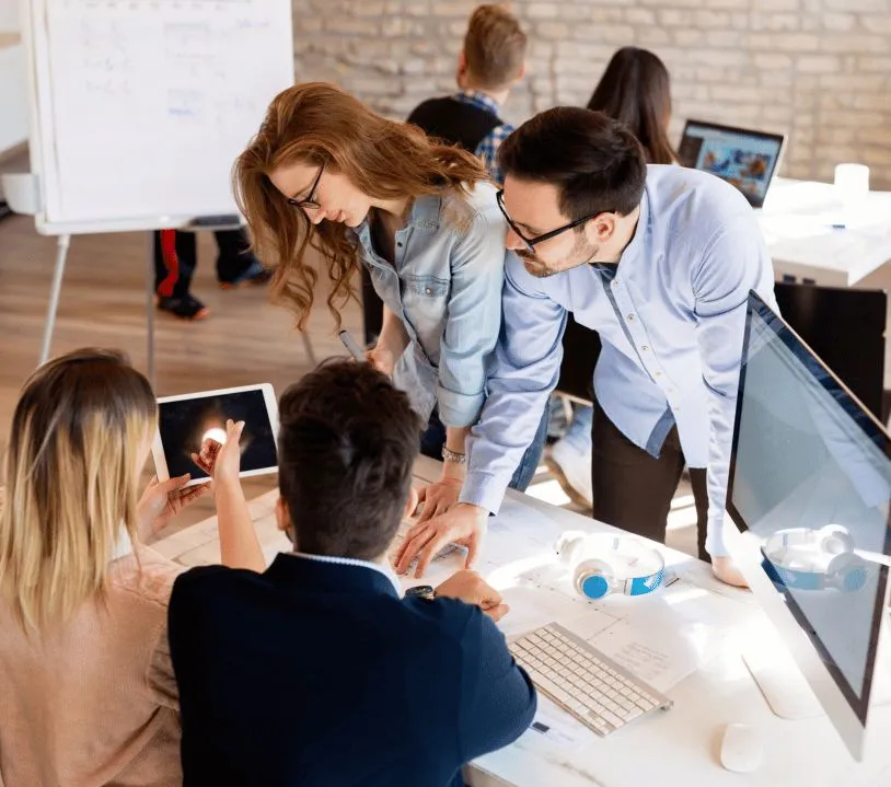 A team collaborating around a desk with laptops